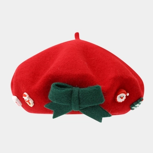 Close-up of red wool beret with green bow and festive Christmas rubber ornaments