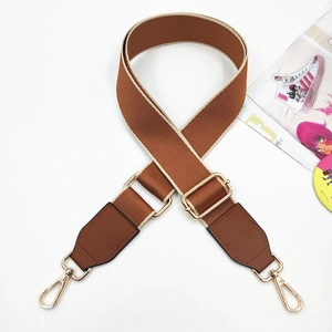 Close-up of brown canvas bag strap with golden metal hooks and adjustable buckle detailing