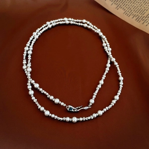 Detail of silver beads and white pearls necklace with a vintage clasp on dark wood