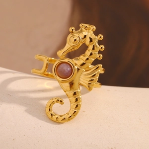 Macro view of gold seahorse ring featuring a purple gemstone and detailed metal texture