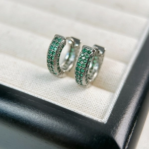 Macro detail of silver hoop earrings with three rows of pavé green emerald zircon stones