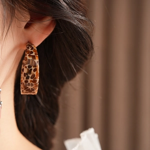 Close-up of leopard print resin hoop earrings worn by model for elegant style