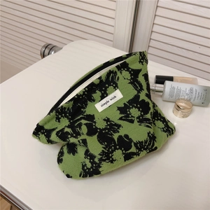 Macro shot of green floral jacquard makeup bag with simple wish logo and zipper detail