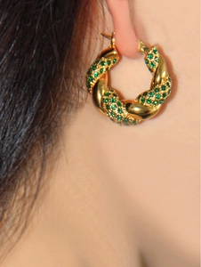 Detail of model wearing a twisted 18K gold stainless steel earring with green zircon gem