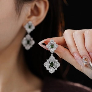 Close-up of vintage silver drop earrings with intricate hollow design and green gemstones