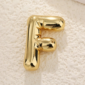 Macro detail of gold bubble letter F pendant with a polished high-shine metallic finish