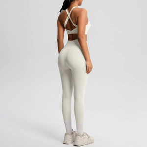 Detalle de sujetador deportivo cruzado y leggings de cintura alta en tela blanca