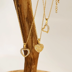 Detailed view of gold heart pendants with zircon inlay on a natural wooden stand