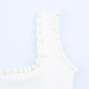 Close-up of white knitted strap with elegant ruffles and polished pearl embellishments