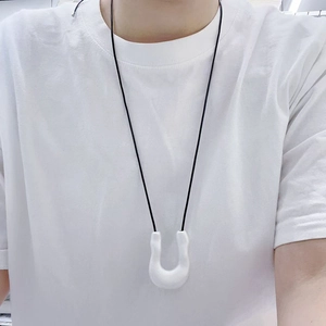 Detail of a white U-shaped minimalist pendant necklace with black cord on a male model