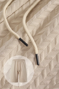 Macro shot of textured knit fabric and drawstring details on beige casual shorts
