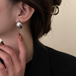 Polished silver hemispherical earrings shown on a model wearing a professional black blazer