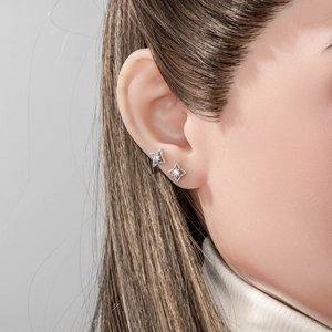 Silver four-pointed star cartilage studs with clear round center stones on model ear