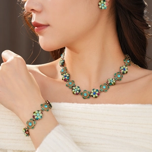 Close-up of vintage bronze necklace and bracelet set with green floral rhinestones
