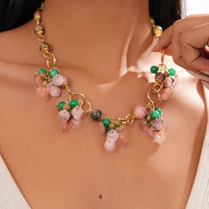 Close-up of bohemian stone beads and golden hoop pendant on a layered sweater necklace