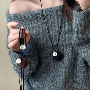 Close-up of velvet heart pendants in black, blue, and brown with Take It Easy metal plates