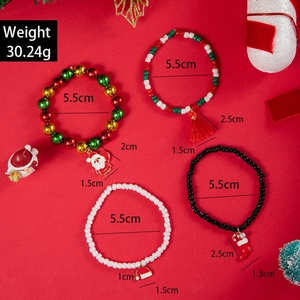 Handmade Christmas beaded bracelets with Santa and reindeer charms on festive red background