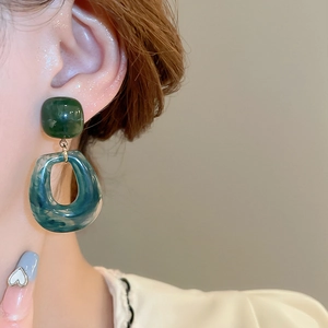 Close-up of geometric resin drop earrings with marble texture on female model