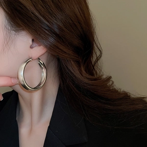 Close-up of model wearing large silver-tone brushed metal hoop earrings with thick walls