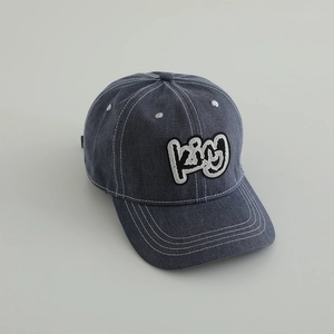 Close-up of blue denim kids baseball cap with white stitching and KING patch embroidery