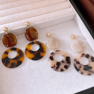 Détails de boucles d'oreilles en résine d'acétate ambre et marbre sur un support à bijoux
