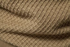 Macro detail of camel cotton knit fabric with waffle texture and thick soft fibers