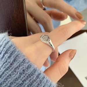 Detailed close-up of a vintage silver sun totem ring with embossed oval surface