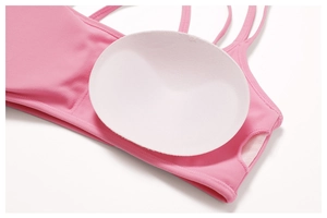 Detailed view of pink yoga sports bra featuring removable pads and mesh lining texture