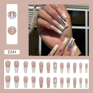 Detail view of long ballet press on nails with French tips, pearls, and rhinestones