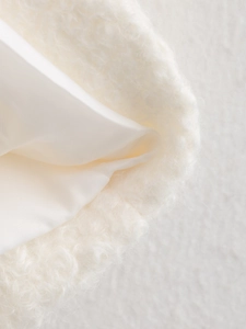 Detailed close-up of white plush faux fur fabric with a silky satin lining texture