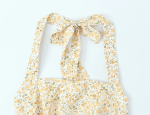 Détail de robe dos nu fleurie montrant l'imprimé jaune et le nœud attaché au cou