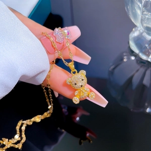 Close-up of a 3D gold bear pendant with micro-pave crystals on a delicate chain necklace