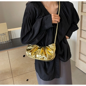 Detail of metallic gold pleated cloud bag worn as a crossbody purse with slim strap