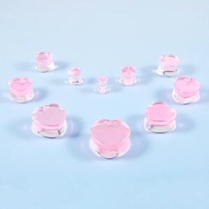 Macro shot of 11 assorted sizes of pink heart-shaped glass ear plugs on blue background