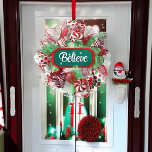 Detailed close-up of a red and green Christmas wreath with a wooden Believe sign