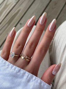 Detail of almond-shaped pearl nails paired with a gold nail-shaped and oval ring