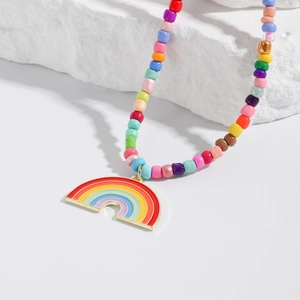 Detail shot of a vibrant colorful seed bead necklace with a heart rainbow pendant on stone