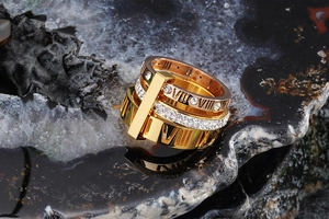Detailed view of gold Roman numeral ring with crystals on a black mineral rock base