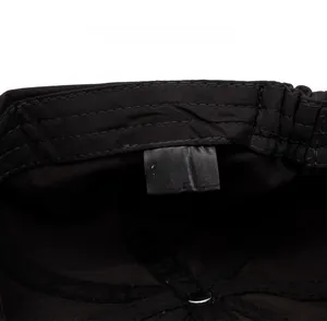 Close-up of the care label on a black cotton newsboy cap showing 100% cotton material
