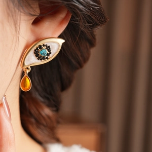 Macro detail of eye-shaped vintage earring with blue heart gemstone and amber drop