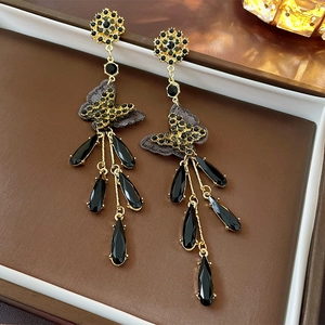 Macro shot of long fringe earrings featuring black crystal drops and mesh bow details