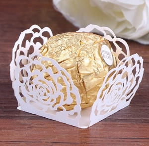 Macro detail of laser-cut white rose paper wrapper for wedding candy and chocolate décor