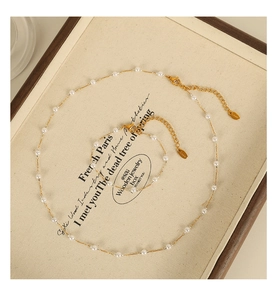 Detail of elegant gold stainless steel chain set with white pearls on a jewelry display