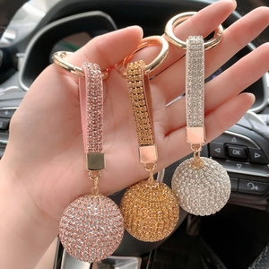 Close-up of pink, gold, and silver rhinestone crystal ball car keychains held in hand