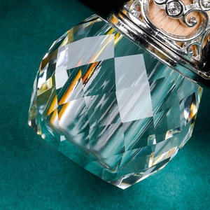 Detailed macro view of diamond-cut crystal perfume bottle with silver hollow metal cap