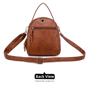 Rear view of brown litchi textured leather crossbody bag with tassel and earphone hole