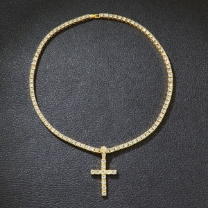 Detail of a gold-plated tennis chain with an iced-out cross pendant on black leather