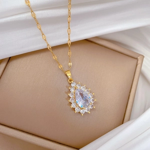 Detail view of gold teardrop pendant necklace and crystal earrings on a jewelry box