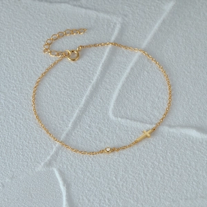 Detail of 925 sterling silver gold bracelet featuring a mini cross and single zircon stone