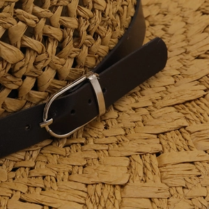 Detailed macro view of hand-woven straw hat with black leather band and silver metal buckle